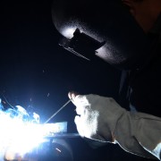 Welder with protective gloves and helmet welding steel